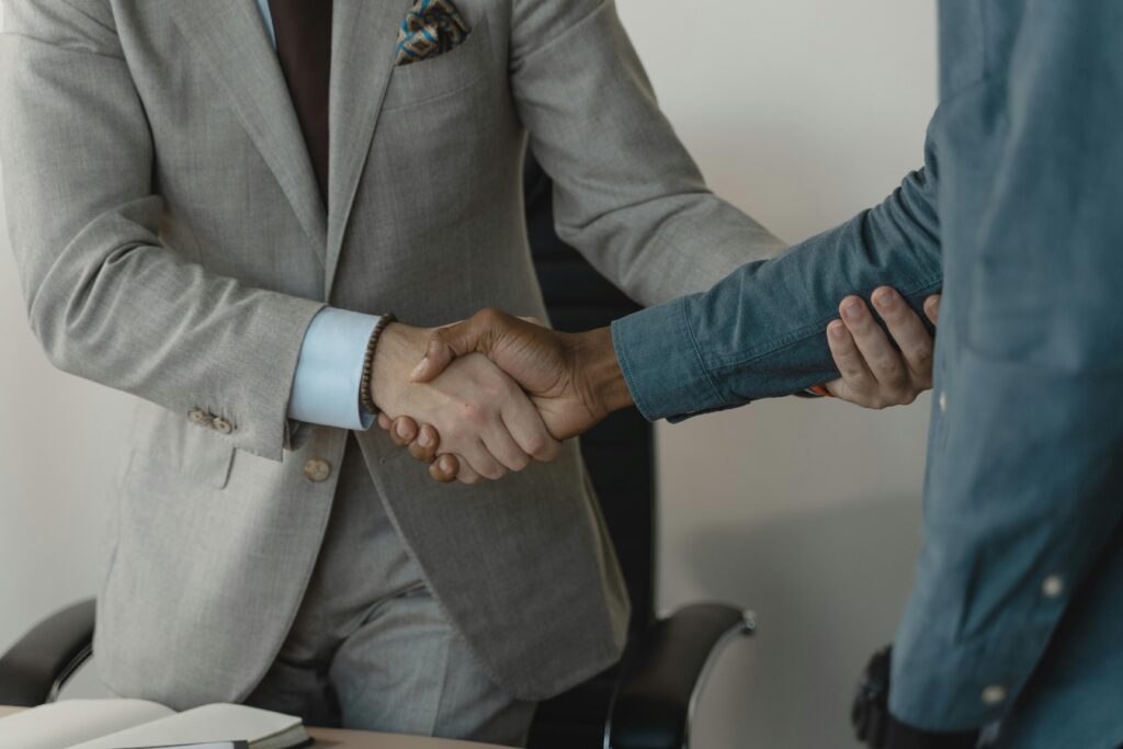 Image of a professional handshake between two businessmen in an office setting.